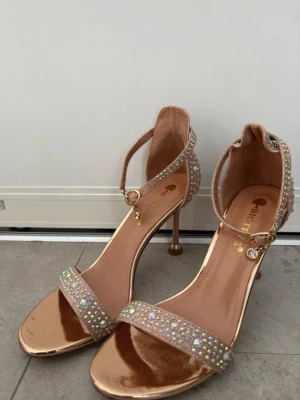 En fin stilig skor  - Säljer ett par eleganta pumps från Bigtree i roséguld med smala remmar dekorerade med gnistrande stenar. 
