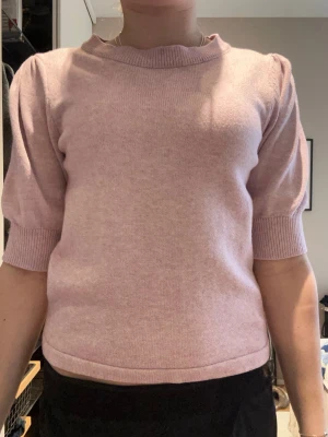 Ljusrosa stickad tröja med puffärm - Söt ljusrosa stickad tröja med korta puffärmar och ribbade muddar vid ärmslut och hals. Tröjan har en rak passform och är tillverkad i ett mjukt material som känns skönt mot huden. Perfekt för en trendig och avslappnad look.❤️❤️har använt 2 gånger innan men de står mitt namn i❤️