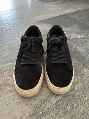 Svarta sneakers från Vagabond - Stilrena svarta sneakers från Vagabond med ovandel i mocka och klassisk vit sula. Skorna har svarta skosnören och låg profil som passar till många olika outfits. Perfekta för dig som gillar en enkel men snygg look.