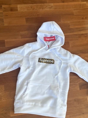 SUPREME HOODIE LEOPARD  - Säljer en helt ny och oanvänd hoodie från Supreme 🤍  Vit hoodie med klassisk box logo i leopardmönster – en riktigt clean men ändå statement piece. Mjuk och bekväm med huva, snören och magficka framtill.  Skick: Helt ny, aldrig använd ✨ Färg: Vit Passform: Klassisk hoodie fit  Perfekt för dig som vill ha en ikonisk Supreme-piece i garderoben.