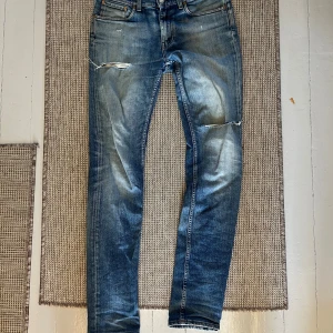 Blå slitna jeans från Acne Studios - Säljer ett par blå jeans från Acne Studios med slitningar och hål på knäna. Riktigt feta och bra skick
