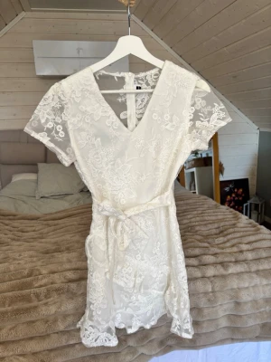 Student klänning Dennis Maglic - Superfin vit kortklänning med v-ringning och knytband i midjan. 