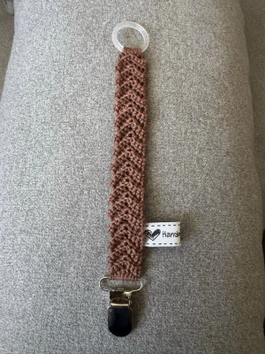 Virkad napphållare  - Virkad, brun napphållare, virkad av mig i 100% bomullsgarn med metallclips och silikonring.  Mönsterskapare: animo.design