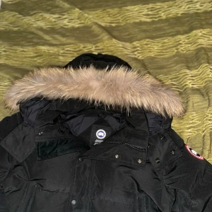 Svart Canada Goose jacka - Säljer min canada goose jacka för att den inte kommer anvöndas sp mycket nu när sommaren kommer och behöver pengar för mat osv. jackan är i nästan prefekt skick inga synliga skador på den samt inga skador på insidan heller. pälsen är avtagbar såklart och luvan är oxå avtagbar jackan passar storlek M men öven L om du är smalare då armarna är lite längre. priset kan diskuteras kom privat flr mer bilder.