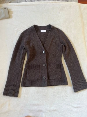 Brun kofta från Wera med fickor - brun kofta från Wera med v-ringning, tre knappar framtill och två fickor. Köpt på åhlens nyligen men jag köpte en ljusbrun istället så säljer denna. Använde den endast 2 gånger så tröjan är som ny!🥰storleken är S