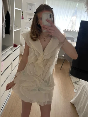 Vit volangklänning - Supersöt vit klänning från NEW COLLECTION med volanger. Jättefin för sommaren. Den är helt ny med lappen fortfarande kvar. Det är storlek L men den passar mig som är 167 och har oftast XS-S, jag tror den passar im man brukar ha XXS-M