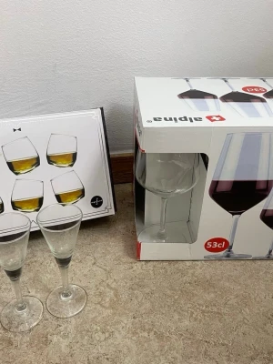 Set med vinglas och whiskeyglas - Säljer ett set med fyra whiskeyglas från Sagaform och fyra stora vinglas från Alpina (53 cl). Glasen är genomskinliga och har modern design, perfekta för hemmabaren eller middagsbjudningar. Båda förpackningarna är med på bilden.