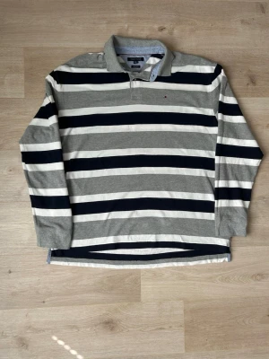 Grå Tommy Hilfiger Piké Tröja Storlek XXL - Fin Tommy Hilfiger tröja i grå färg. Tröjan är i bra skick och sparsamt använd. |  Äkta som allt annat jag säljer! ✅ |  Storlek: XXL | Skick: Bra Skick - Tyvärr en del mindre fläckar, med rätt medel så går de nog bort! | Färg: Grå | Märke: Tommy Hilfiger | Modell: Tröja |  Hör gärna av dig vid frågor så svarar jag så fort jag kan! 😁|   (SKU - 89)