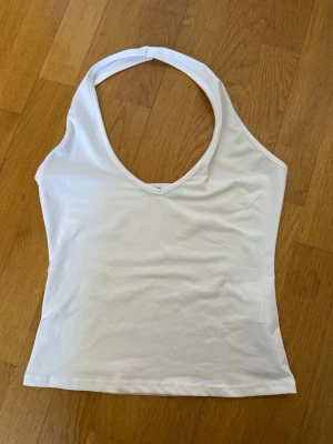 Vit halterneck linnetopp från SHEIN - Säljer en vit halterneck linnetopp från SHEIN i storlek XS. Toppen är ärmlös med djup v-ringning och har en enkel, stilren design. Perfekt till sommaren och lätt att matcha med olika outfits. Tar emot prisförslag 