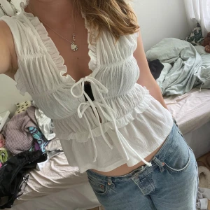 Vit blus med volanger och knyt - Supersöt vit blus med volanger och två knyt framtill. Endast använd ett fåtal gånger och inga synliga defekter.💕