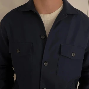 Eton overshirt - Marinblå overshirt från Eton i storlek L. Mycket fint skick, knappt använd. Säljer den då den är lite för stor. Liten i storleken för att vara L. Skulle säga att den passar dem som har storlek M eller L.