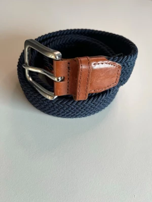 Marinblå bälte från Jack & Jones - Säljer ett snyggt marinblått flätat bälte från Jack & Jones med bruna skinn-detaljer och silverfärgat spänne. 