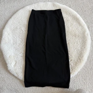 Svart långkjol (XS) - En enkel och stilren svart långkjol. Kjolen har rak passform och slits baktill för extra rörelsefrihet. Perfekt för dig som gillar minimalistisk och clean look.