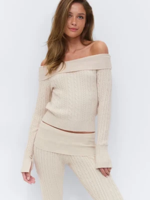 Beige off shoulder stickad tröja från Gina Young  - Oanvänd trendig beige stickad tröja med off shoulder-design och bred ribbad kant upptill. Tröjan har kabelstickat mönster och långa ärmar med ribbade muddar. Perfekt för en snygg och avslappnad look.