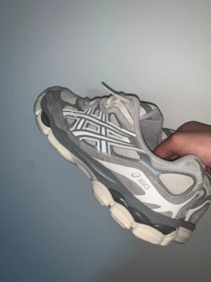 Asics Gel NYC gråa - SKO KARTONGEN TILLKOMMER❗️✅LITE SKADA INUTI SKON VID HÄLEN MEN DET KÄNNS INTE OCH SYNS INTE. Säljer ett par gråa Asics sneakers med vit sula och detaljer i mesh och mocka. Skorna har klassiska Asics-loggan på sidan och en chunky sula som ger en sportig vibe. Perfekta för dig som gillar streetwear och bekväma skor. 