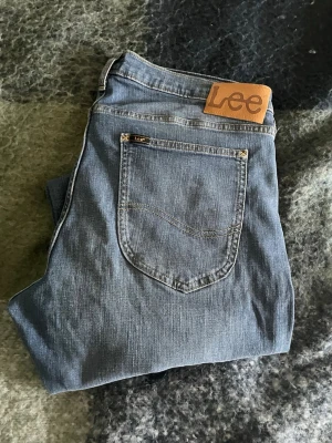Blå jeans från Lee med rak passform - Säljer ett par klassiska blå jeans från Lee med rak passform. Jeansen har fem fickor, normal midja och Lee-logga på bakfickan. Tillverkade i slitstark denim som passar perfekt till vardagslooken.