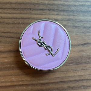 YSL Make Me Blush Rouge - Lyxig rouge från YSL i nyansen Make Me Blush, med en snygg rosa färg och skimrig finish. Kommer i en rund, guldig dosa med quiltad ljusrosa ovansida och YSL-logga i metall. Inuti finns spegel och pressat puder med YSL-prägling.