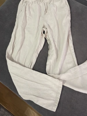 Ett par bescha  linnebyxor med resår - Säljer ett par bescha  linnebyxor med breda ben och resår i midjan. Byxorna har en avslappnad passform och en bakficka. Perfekta för en chill och luftig stil. Materialet är linne vilket gör dem svala och sköna.
