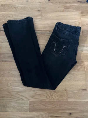 Svarta jeans från Gina Tricot - Jag säljer ett par svarta jeans från Gina tricot med kristaller på fickorna. Byxorna är ganska low waist. Jag är 159cm lång och dessa jeans sitter perfekt i längden