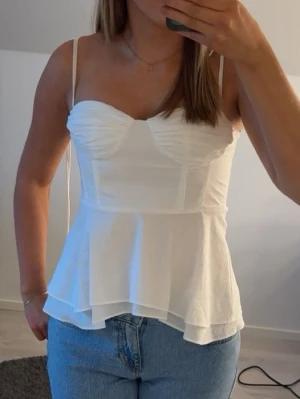 Vit korsettopp med tunna band - Vit topp ifrån Zara. I storlek xs. Använd en gång.