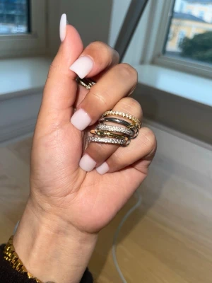 Mixade ringar i silver och guld vattentålig rostfritt stål - Säljer ett set med flera ringar i både silver- och guldfärg. Vissa ringar har gnistrande stenar runt hela ringen och andra är släta eller har tvinnad design. Perfekt för dig som gillar att mixa olika stilar och bära flera ringar samtidigt. Det finns storlek 7 och 8 samt 9 ett exemplar av varje.