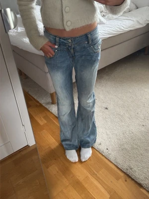 Blå bootcut jeans med låg midja - Säljer ett par ljusblå bootcut jeans med låg midja och slitningar framtill. Perfekta för en avslappnad och trendig stil. Säljer pga att dem inte kommer till användning, Skriv för fler frågor!