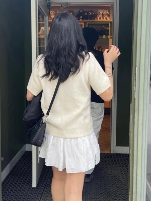 Krämvit kortärmad kofta med knappar - Säljer en krämvit, kortärmad kofta med rund hals och knäppning framtill. Koftan har en mjuk, stickad känsla och ribbade kanter vid ärmslut och nederkant. Perfekt för lager-på-lager och enkel att styla till olika outfits.