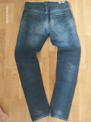 Blå slim fit jeans med slitningar - Snygga blå jeans med lätt slitna detaljer och kontrastsömmar. Jeansen har klassiska fem fickor, dragkedja och knapp i midjan samt coola detaljer på bakfickorna. Perfekta för en avslappnad och trendig look.