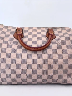 Louis Vuitton Speedy 30 - Louis Vuitton Speedy Damier Azur 30. Väskan är vintage och köpt på Vestiaire Collective, den har blivit verifierad av experter på deras äkthetsteam. Läderhandtagen har fått en vacker och fin patina och Damier Azur canvasen har övergått en aning från den nya, vita färgen till en mer använd ton. Väskan är generellt sätt i ett mycket bra skick. Skriv för fler bilder, frågor eller äkthetsbevis! 🩷