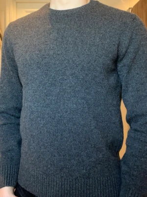 Grå Merinoull Tröja - Säljer en stilren grå stickad tröja från Colorful Standard som är 100% återvunnet Merino ull. Tröjan har rund halsringning, långa ärmar och ribbade muddar vid ärmslut och nederkant. Perfekt basplagg i mjukt material som passar till det mesta. Tröjan är Storlek S men sitter som XS. 