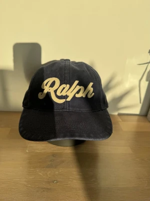 Mörkblå Polo Ralph Lauren keps - Säljer en keps från Polo Ralph Lauren, one size. Den är använd men i bra skick utan defekter. Gjord i bomull med justerbart spänne där bak i cow leather.