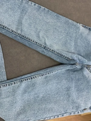 Ljusblå mom jeans från FOG - Säljer ett par ljusblå mom jeans från FOG med klassisk femficksdesign och raka ben. Jeansen har en snygg tvättad look och är tillverkade i denim. Perfekta för en avslappnad och trendig stil.