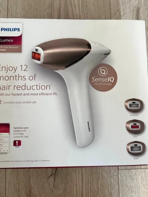 Philips Lumea IPL hårborttagningsapparat - IPL hårborttagningsapparat från Philips Lumea med SenseIQ-teknologi. Vit och roséguld design, ergonomiskt handtag och flera utbytbara munstycken för precision, ansikte och kropp. Sladdlös och sladdansluten användning möjlig.