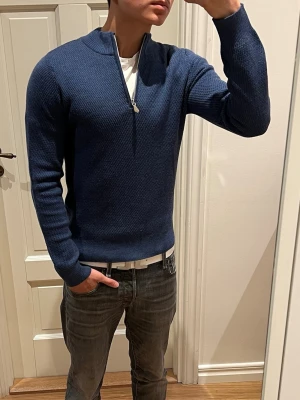 Blå quarterzip tröja från Stenströms - Snygg blå stickad tröja från Stenströms med quarterzip och ribbad krage. Material: 100% merinoull. Använd fåtal gånger, inga defekter. Skriv vid minsta fundering! 