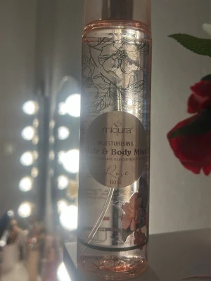 Miqura Hair & Body Mist Rose - Fräsch och återfuktande hår- och kroppsmist från Miqura med doft av ros. Flaskan är genomskinlig med blommigt mönster och rosa detaljer. Perfekt för dig som vill ha en lätt och blommig doft i vardagen