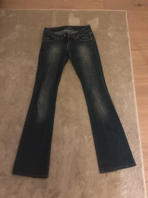 Bootcut jeans från Big Star - Mörkblå bootcut jeans från Big Star med snygga slitningar framtill och klassiska fickor bak. Jeansen har låg midja och kontrastsömmar som ger en cool look. Perfekta för dig som gillar en avslappnad men trendig stil. 