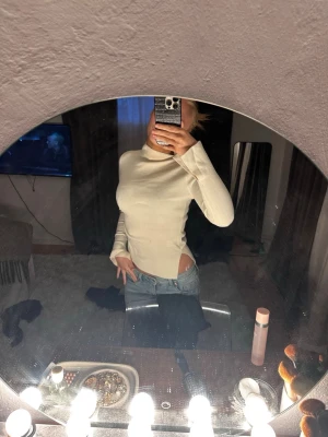 Vit ribbad polotröja med cut out - Trendig vit polotröja med ribbade detaljer och cut out på sidan. Tröjan har lång ärm och en tight passform. Perfekt till en utekväll eller till en middag!