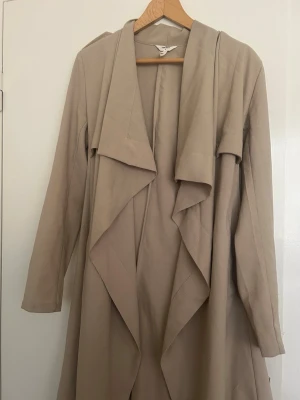 Beige trenchcoat  - Säljer en stilren beige trenchcoat från Object. En klassisk och tidlös kappa som passar perfekt till våren och hösten. Den är lätt att matcha och funkar både till vardag och lite mer uppklätt.  Kappan är i fint skick och har använts varsamt.