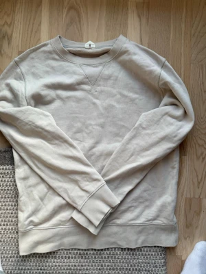 ARKET sweatshirt - Säljer en enkel och stilren beige sweatshirt i bomull från ARKET. Tröjan har rund halsringning, ribbade muddar vid ärmslut och nederkant. Perfekt för dig som gillar en clean och avslappnad look.