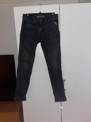 Svarta jeans från Replay - Säljer ett par svarta jeans från Replay. Jeansen har en tvättad look och är tillverkade i denim, vilket ger en skön och avslappnad stil. Knappt använda och inga defekter! Hör av dig för fler bilder!