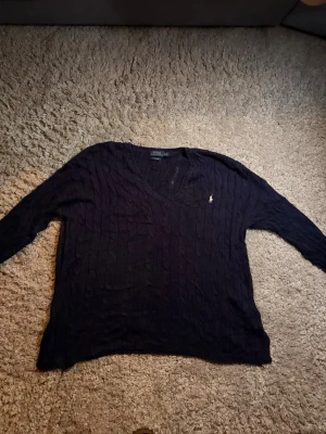 Mörkblå kabelstickad tröja Polo Ralph Lauren - Ralph Lauren stickad tröja, större storlek LG. Finns defekt i nacken av tröjan. Vid frågor skicka ett meddelande 