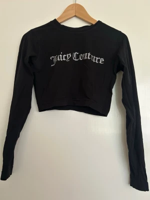Svart Juicy Couture croptop - Juicy Couture croptop med glitterlogga. Väldigt fin på och bra skick. Säljer då den inte kommer till användning.