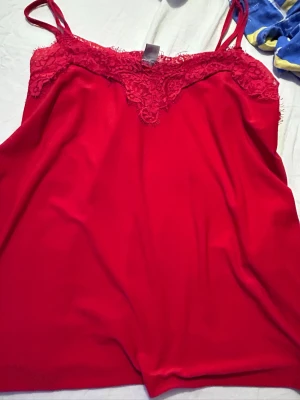 Rött nattlinne med spetsdetaljer - Snyggt rött nattlinne med tunna axelband och vacker spets upptill. Mjukt och följsamt material som känns skönt mot huden. Perfekt för en mysig kväll hemma. Spetsen ger en extra touch av elegans.