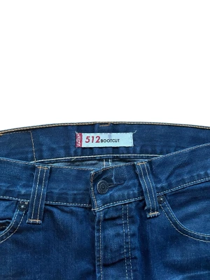 Levi's 512 Bootcut jeans blå - Säljer ett par 512 Levis i mörkblå färg strlk 32/32. Jeansen har en trendig bootcut passform och klassisk femficksdesign. Modellen är unik och svår att få tag på då den inte produceras längre. Förutom några riktigt snygga slitningar/veck vid fickorna och fållen är dom i toppenskick, som nya! Mått: (+- någon centimeter då jag mäter för hand) midja: 42.5cm längd: 103cm benöppning: 23.5cm  Skriv om det finns frågor eller funderingar!