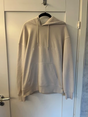 Beige hoodie från Jack and Jones - Säljer en beige hoodie från Jack and Jones med broderad logga på bröstet. Tröjan har en stor huva med dragsnören och en klassisk magficka. Materialet är mjukt och bekvämt, perfekt för chill dagar. Ribbade muddar vid ärmslut och nederkant. Acceptabelt skick, hör av er om ni har frågor.