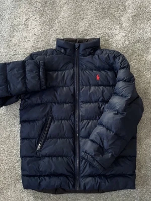 Ralph Lauren Jacka - Hej! Säljer min Ralph Lauren Jacka för att den har blivit för liten. Nypris ~ 4000kr. Den har en avtagbar luva som är väldigt bra om det är lite ruggigt väder ute. Den har en Polo logga på Höger arm. Perfekt för en lite stiligare look nu till våren! Skriv om ni vill ha mer bilder eller om ni har några frågor! Jag svarar Snabbt :)  P.S! Kan gå ner i pris vid snabb affär🍾🔥💯