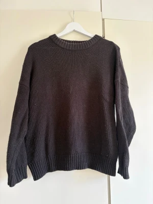 Svart stickad tröja från Stay - Svart stickad tröja från Stay med avslappnad passform och ribbade muddar vid ärmslut, halsringning och nederkant. 