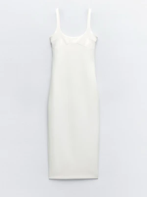 Vit midiklänning från Zara - Säljer en stilren vit långklänning från Zara med smala axelband och figurnära passform. Dragkedja i ryggen Materialet känns mjukt och lätt, vilket gör den bekväm att bära. Helt ny med lappar kvar. Har en likadan i stl S i annan annons. 