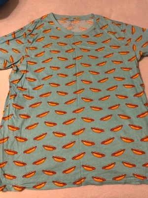 T-shirt med varmkorv - T-shirt med varmkorvstryck från Biltema. Endast använd någon enstaka gång så i absolut nyskick. Dock liten i storlek så skulle hellre säga strl M.