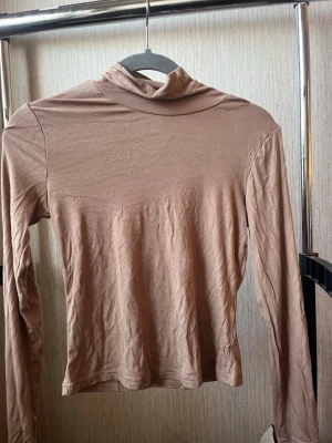 Beige polotopp med lång ärm - Beige polotopp med lång ärm och smal passform. Mjuk och stretchig känsla, enkel att matcha med andra plagg.